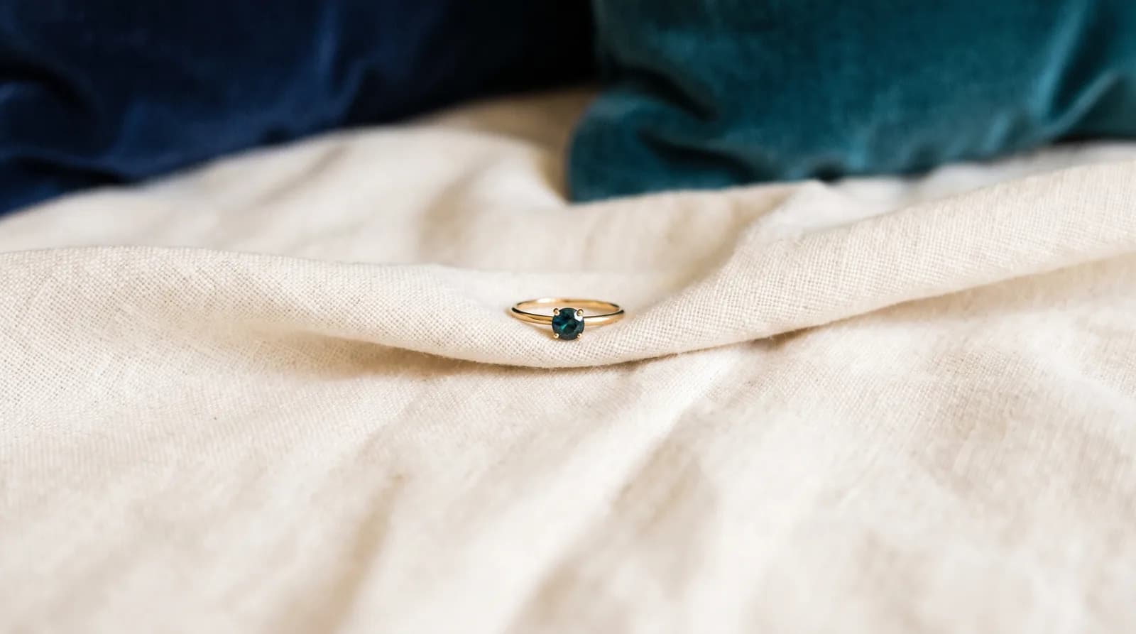 Anillo con piedra verde sobre un paño de lino claro.